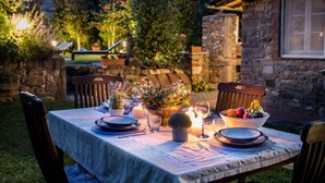 An outdoor dining setup with a table set for two, surrounded by stone walls and greenery. - Villa Coccinelle in Pieve di Compito (Capannori)
