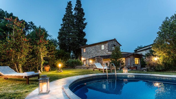 A stone house with a swimming pool, surrounded by trees and outdoor seating. - Villa Coccinelle in Pieve di Compito (Capannori)