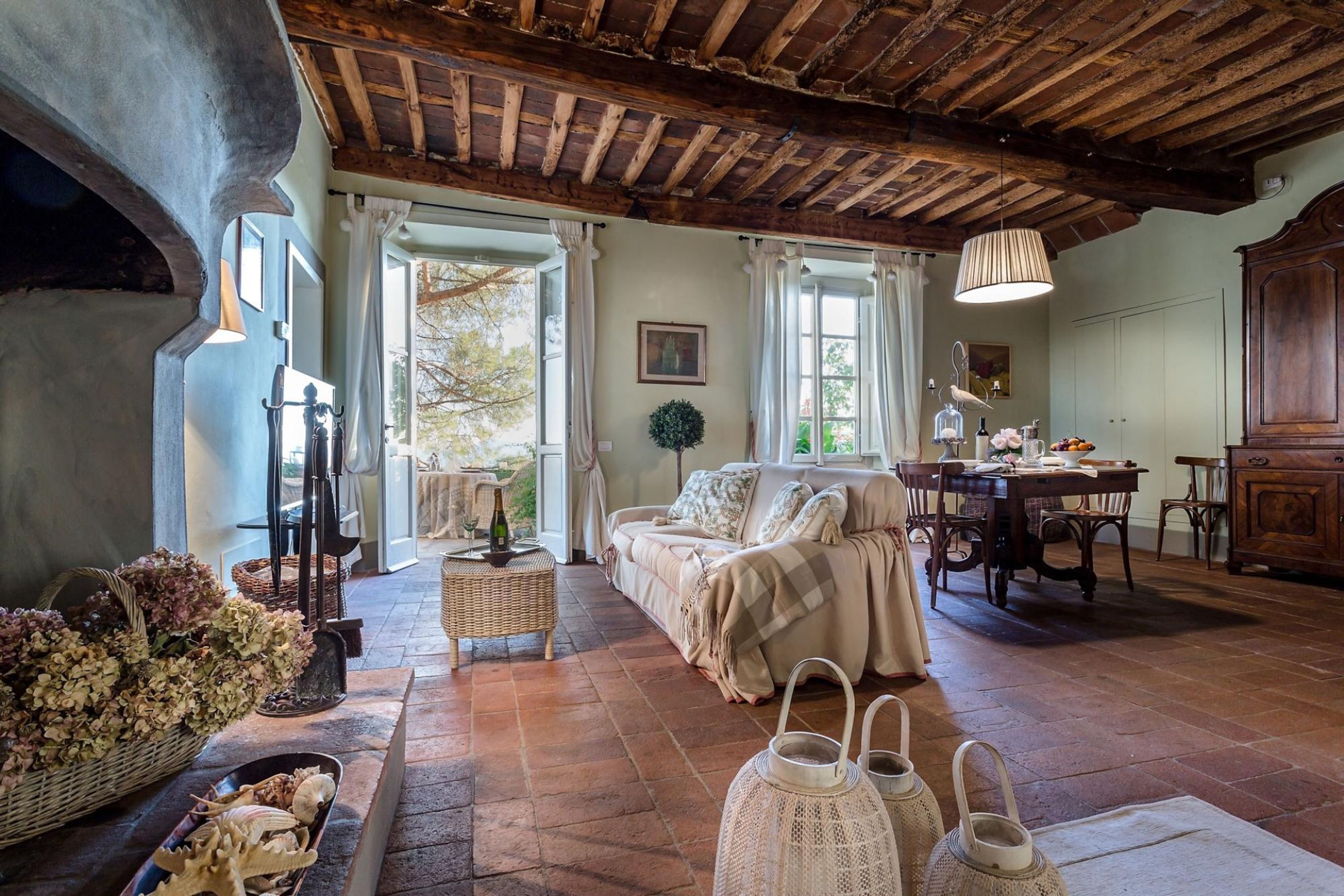 A rustic room with a wooden ceiling, a sofa, a dining table, and wicker baskets.