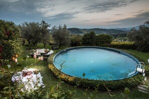 Relax by the serene pool surrounded by lush greenery and rolling hills.
