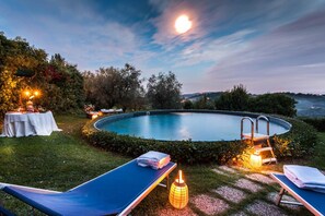 Relax by the serene pool surrounded by lush greenery and a tranquil lake view.