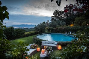 Relax by the serene pool surrounded by lush greenery and a comfortable seating area.