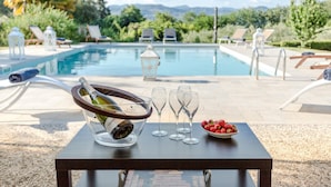 A poolside table with a champagne bottle, glasses, and strawberries. - Villa Gattaiola in Gattaiola (Lucca)