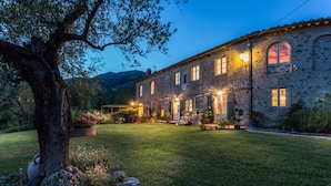 A stone building with a well-maintained lawn and potted plants. - Villa Il Palagio in Capannori (Capannori)