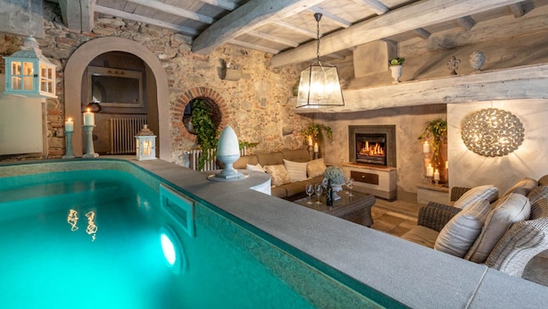 A cozy indoor pool area with stone walls, a fireplace, and comfortable seating. - Villa Il Palagio in Capannori (Capannori)