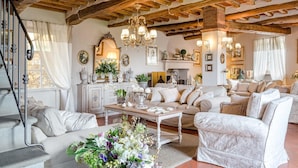 A spacious living room with a high wooden ceiling, a fireplace, and a staircase. - Villa Il Palagio in Capannori (Capannori)