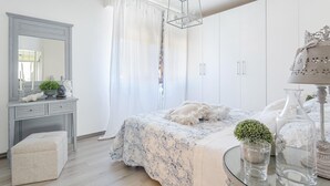 A bedroom with a bed, a vanity with a mirror, a dresser, and a hanging light fixture. - Villa Marygrace in Forte dei Marmi (Forte dei Marmi)
