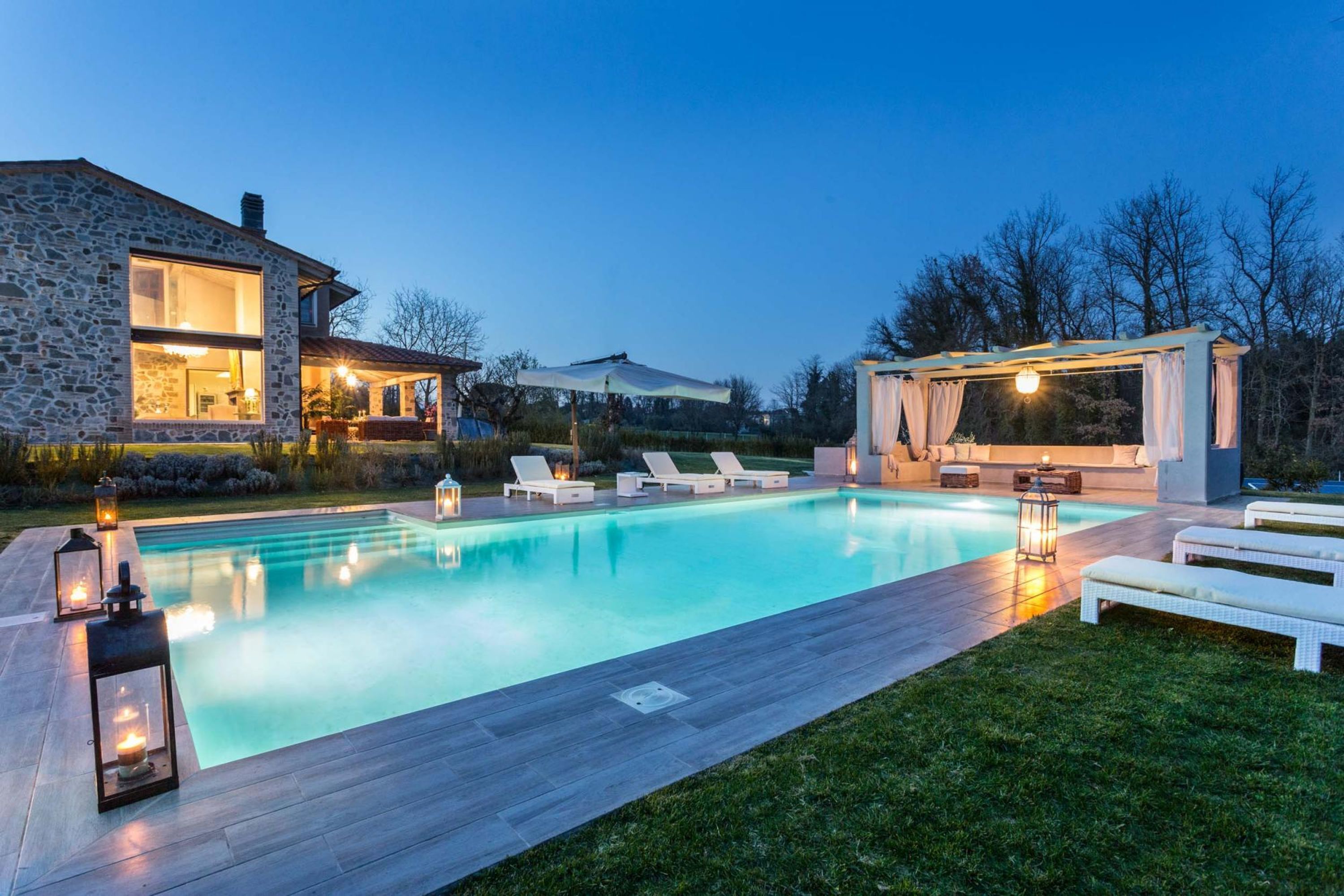 Ein modernes Haus mit Swimmingpool, Sitzgelegenheiten im Freien und einer Pergola.