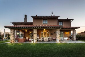 A two-story house with a patio area, outdoor furniture, and a barbecue setup.