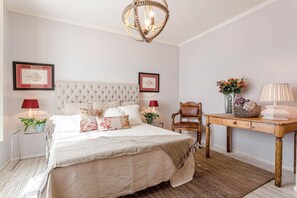 A bedroom with a large bed, two bedside tables, a wooden chair, a desk, and a chandelier. - Villa Otto in Orentano (Castelfranco di Sotto)