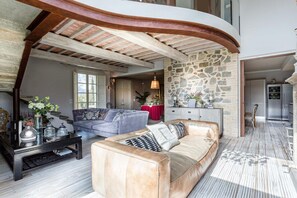 A spacious living area with a curved ceiling, a stone wall, and a modern kitchen in the background. - Villa Otto in Orentano (Castelfranco di Sotto)