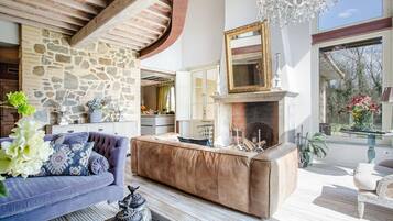 A spacious living area with a stone wall, a fireplace, and a large mirror above it.