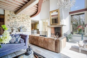 A spacious living area with a stone wall, a fireplace, and a large mirror above it.