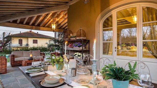 An outdoor dining area with a table set for two, surrounded by potted plants and a cozy seating arrangement. - Villa Otto in Orentano (Castelfranco di Sotto)