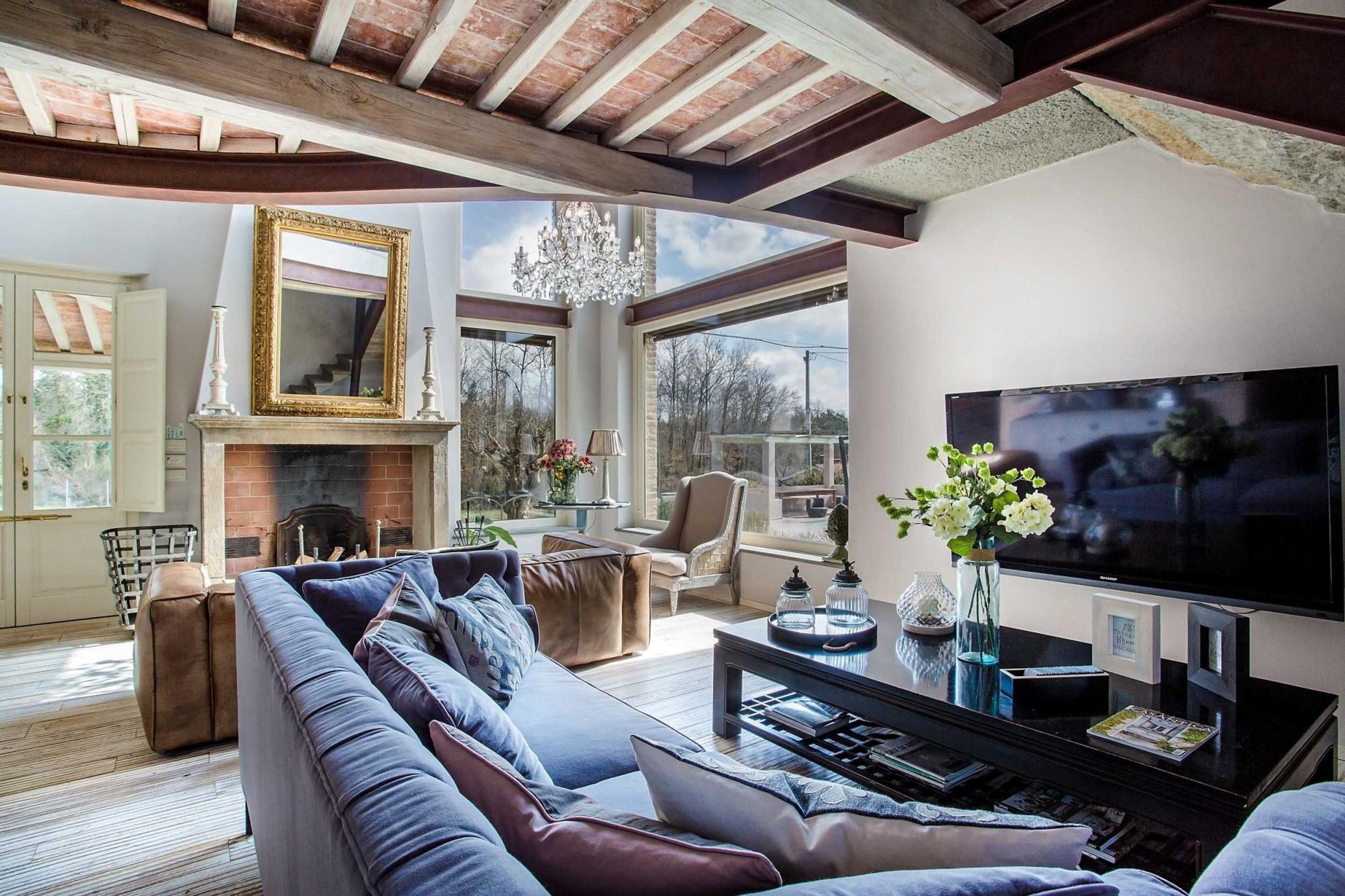 A living room with a fireplace, a large sofa, a television, and a chandelier.