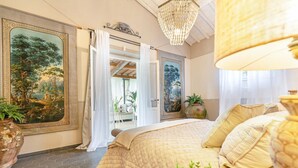 Una camera da letto con un letto grande, un lampadario e due quadri alle pareti.