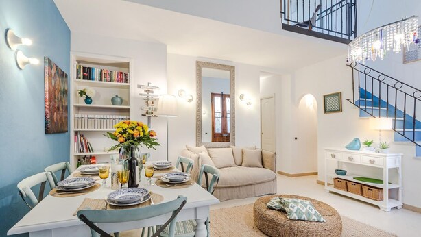A modern living room with a dining area, a staircase, and a bookshelf. - Villa Paola in Viareggio (Viareggio)