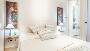 A neatly arranged bedroom with a bed, pillows, a nightstand, and a wall-mounted lamp. - Villa Paola in Viareggio (Viareggio)