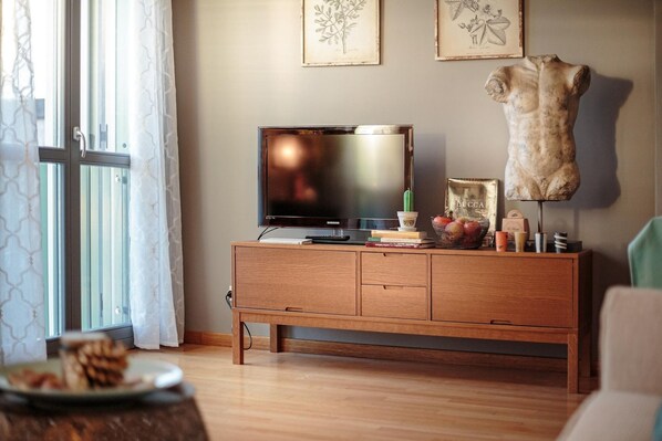 A living room with a wooden TV stand, a mounted animal head sculpture, and framed artwork on the wall.