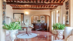 A spacious hallway with a polished marble floor, a wooden ceiling, and a dining area with a table and chairs.