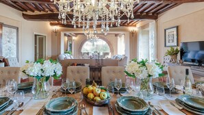 A dining area with a chandelier, round table, and chairs.