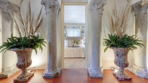A corridor with three columns, leading to a bedroom with a bed and a nightstand. - Villa Viola Residenze Seicento (Capannori)