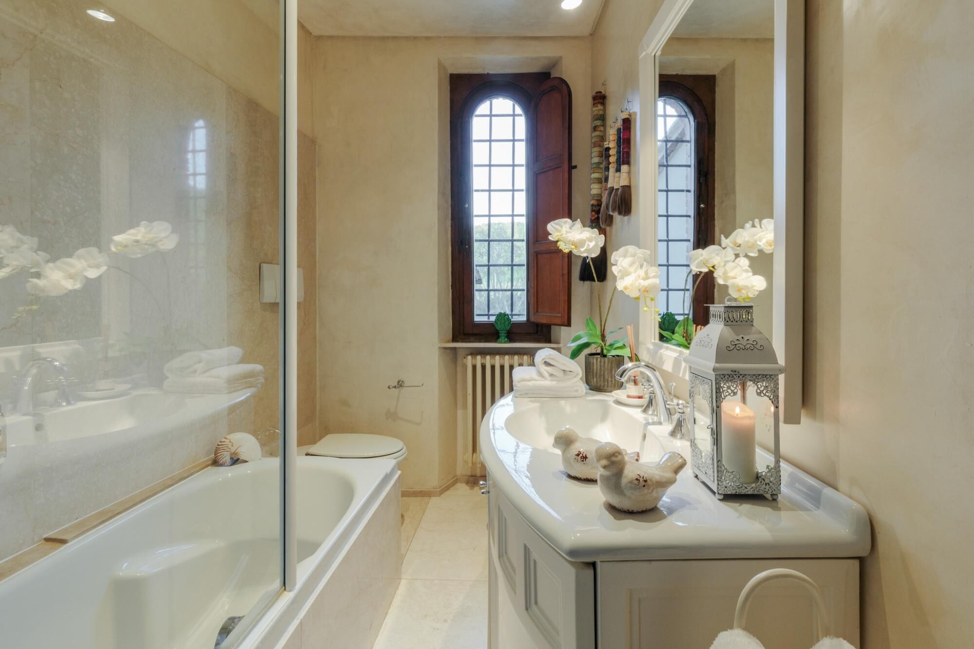 Een badkamer met een wastafel met twee kommen, een bad, een toilet en een raam met uitzicht.