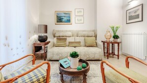 Un salon comprenant un canapé, deux fauteuils, une table basse et une petite table d’appoint avec une lampe et une plante.
