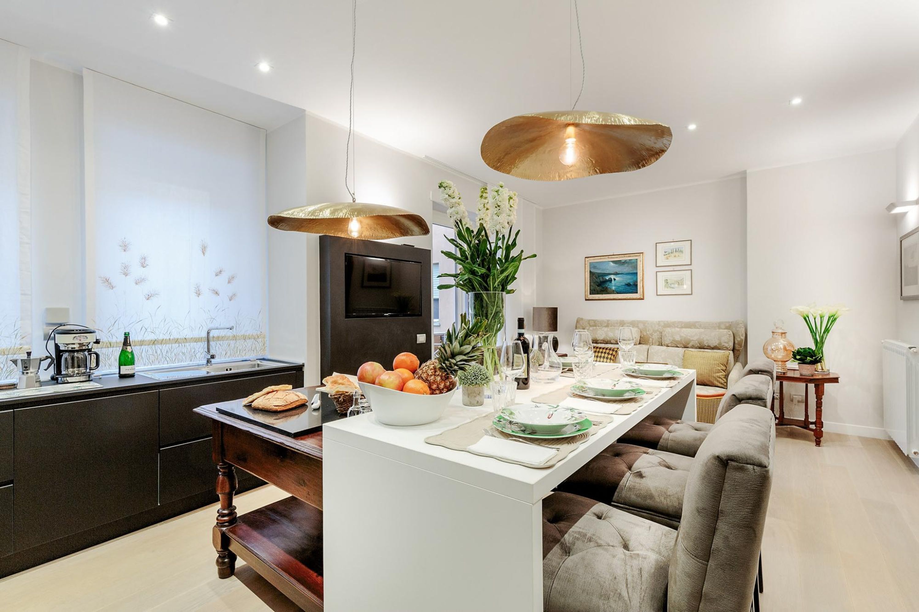 A modern kitchen with a central island, dark cabinetry, and pendant lighting.