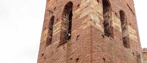 A tall brick tower with arched windows and a clock.