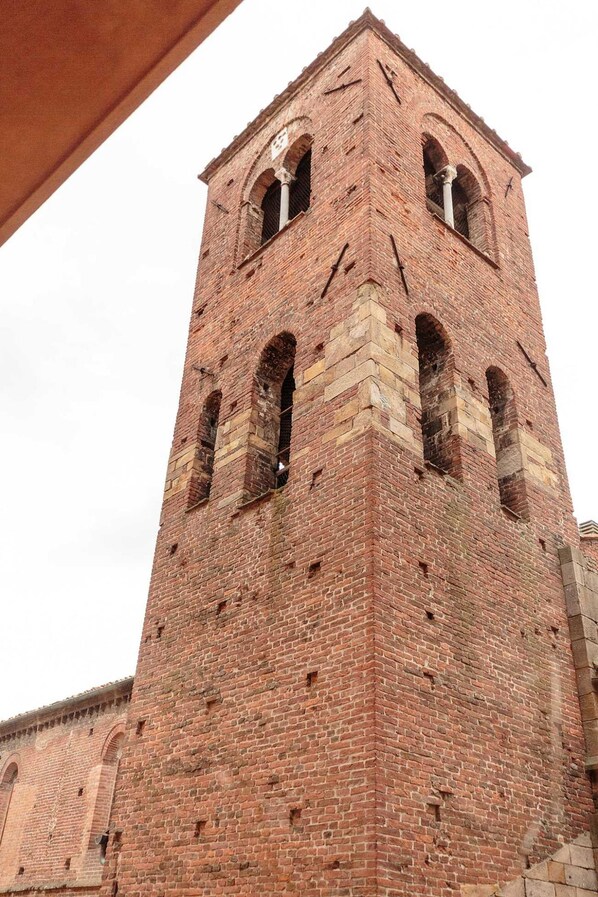 A tall brick tower with arched windows and a clock. - The Palace View in Lucca (Lucca)