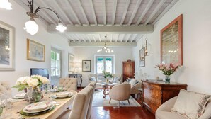 A dining area with a long table set for a meal, surrounded by comfortable seating. - Villa D Amico in Lucca (Lucca)
