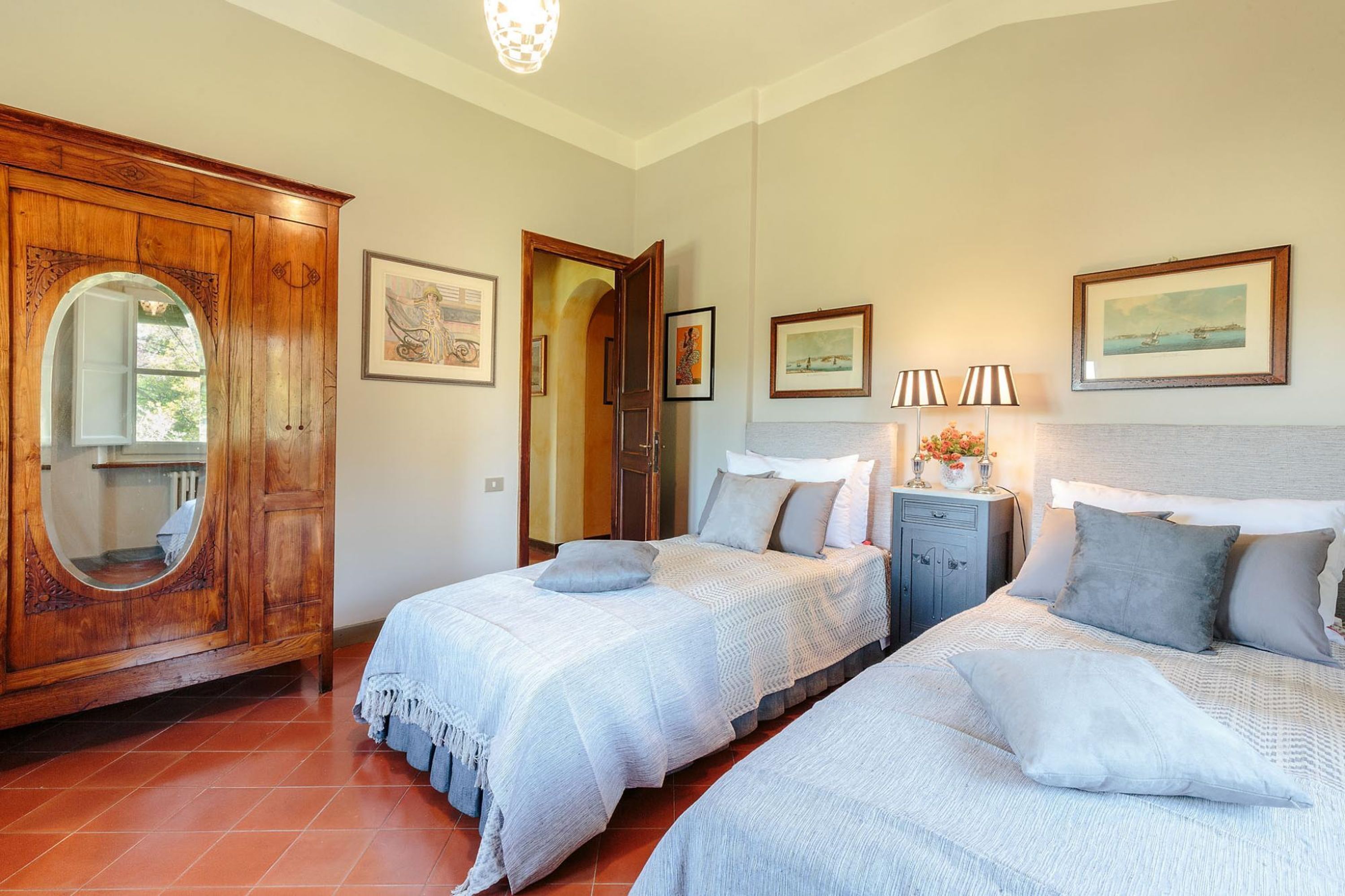 Un dormitorio con dos camas, un armario de madera y obras de arte enmarcadas en las paredes.