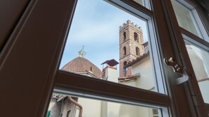 A view through a window of a building with a brick tower and a dome. - The Puccini Penthouse (Lucca)