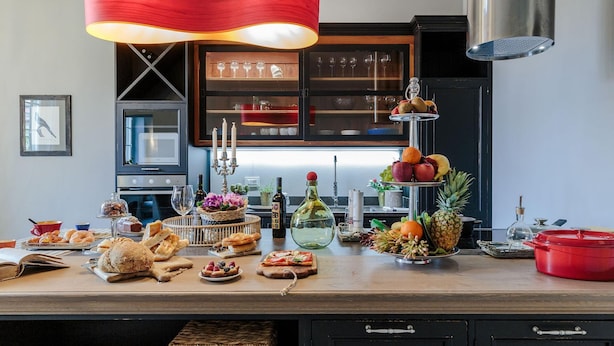 A kitchen with a wooden countertop, a red hanging light, and various food items and kitchenware. - The Puccini Penthouse (Lucca)