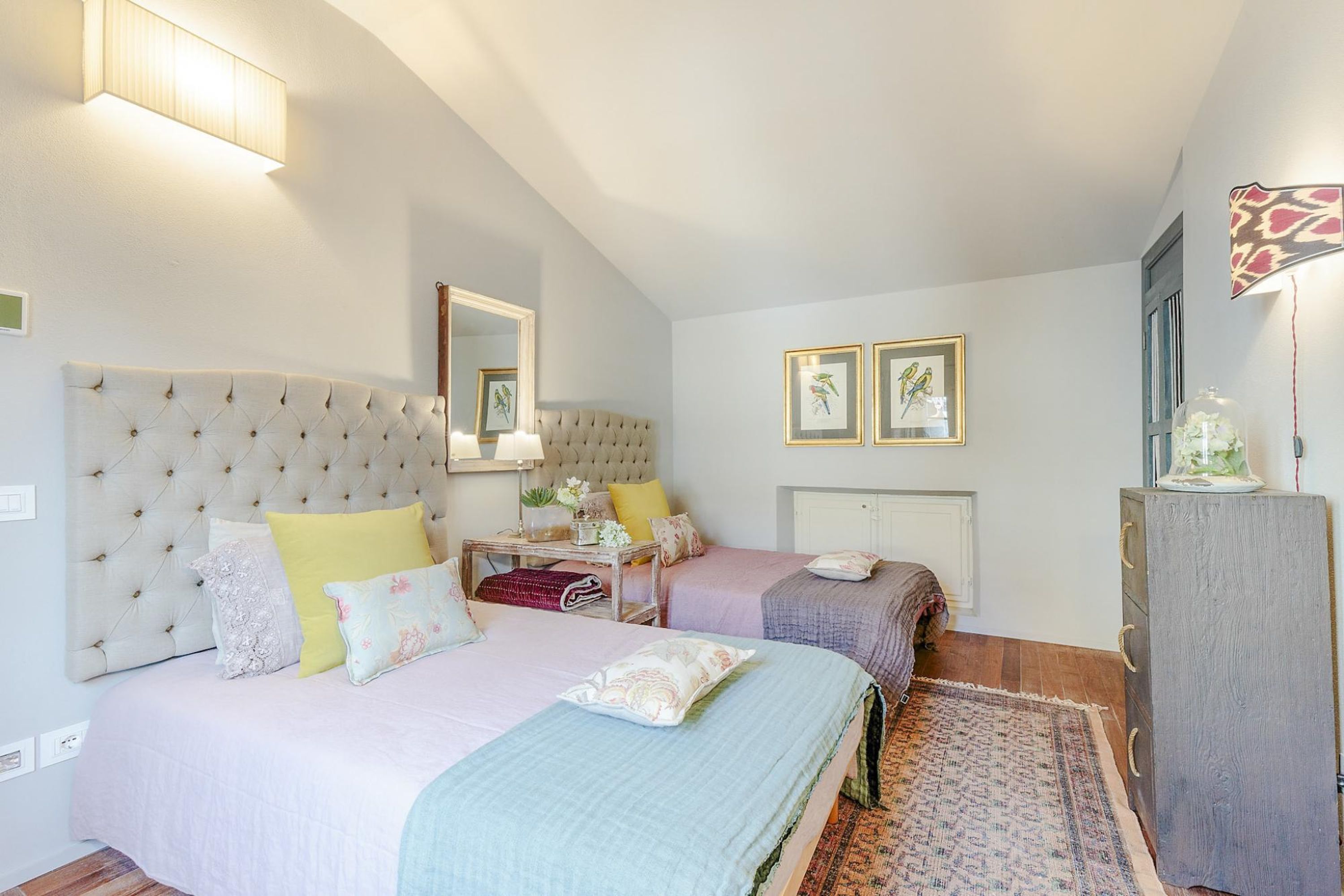 A bedroom with two beds, a dresser, a mirror, and framed pictures on the wall.