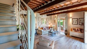 A spacious living area with a wooden staircase, a sofa set, and a dining table. - Villa Pemola in Capannori (Capannori)