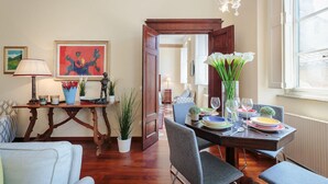 A dining area with a wooden table set for four, surrounded by chairs. There is a chandelier above the table, and a painting on the wall to the left. - Casa Santa Croce in Lucca (Lucca)
