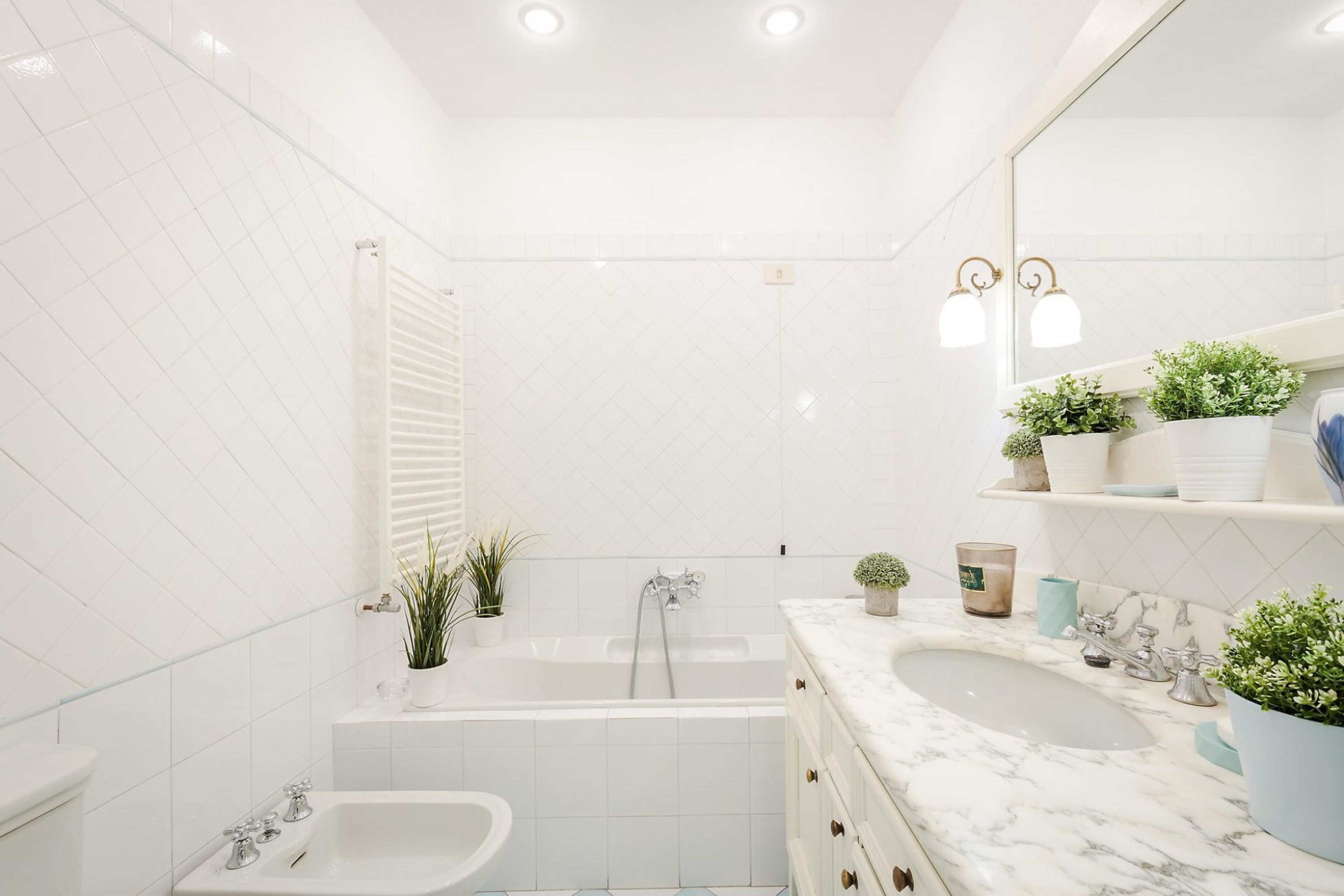 Une salle de bain moderne avec une baignoire, un lavabo sur pied et un meuble-lavabo avec un miroir.