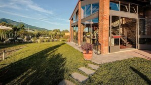 A modern house with a large glass facade, a brick exterior, and a well-maintained lawn. - Villa Ricordi in Marlia (Capannori)