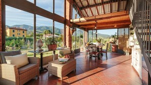 A spacious patio with wicker furniture, a dining table, and a view of the countryside. - Villa Ricordi in Marlia (Capannori)