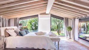 A bedroom with a large bed, a bench, and a view of the outdoors. - Villa Matilde in Capannori (Capannori)