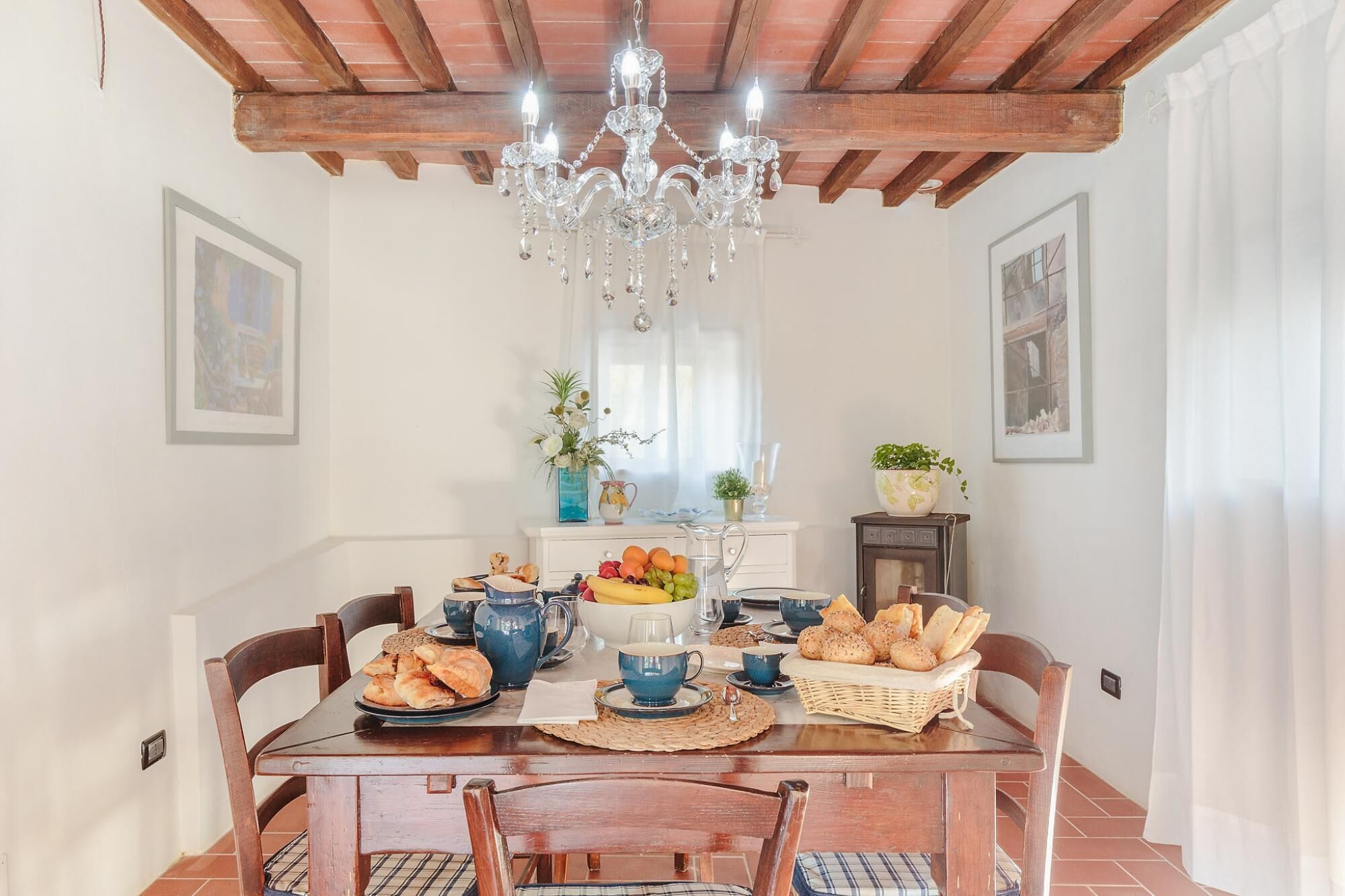 Une table à manger agrémentée d’un lustre, de tableaux encadrés, ainsi que d’une variété de plats et de boissons.