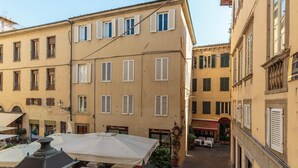 A narrow street with buildings on either side, featuring outdoor seating areas with tables and umbrellas. - Casa Arias in Lucca With 2 Bedrooms and 1 Bathrooms (Lucca)