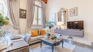 A living room with a sofa, coffee table, and dining area set up with plates and glasses. - Casa Arias in Lucca With 2 Bedrooms and 1 Bathrooms (Lucca)