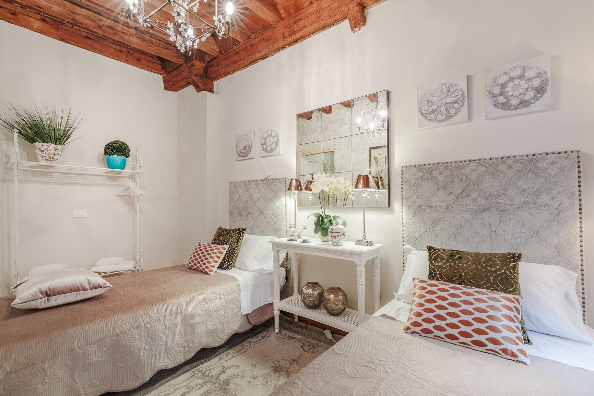 A bedroom with two beds, a vanity, and decorative wall art.