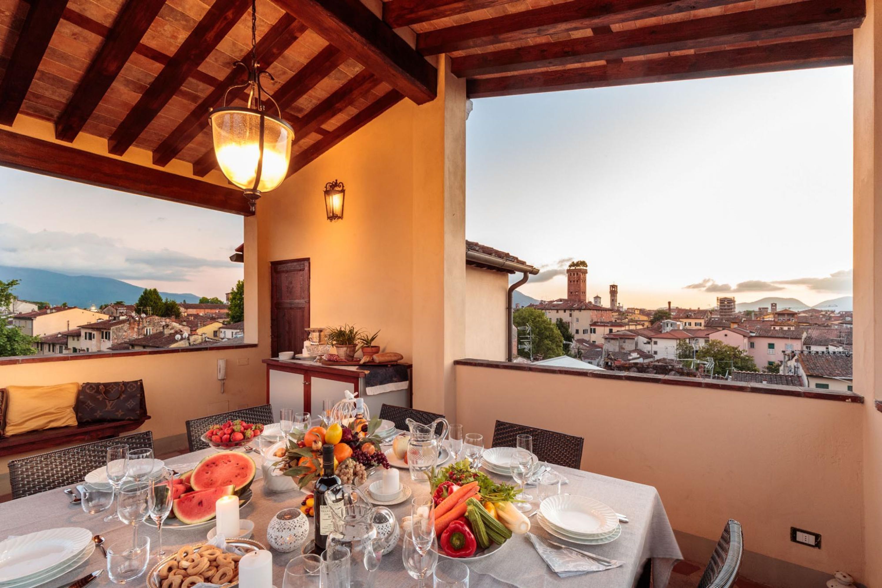 Una mesa de comedor preparada para una comida, con vistas a la ciudad y montañas al fondo.