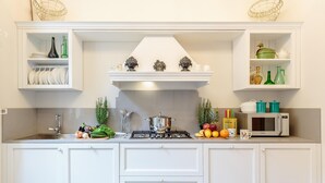 A kitchen with white cabinetry, a stove, a microwave, and various kitchen items on the counter. - The Park View Apartment (Lucca)