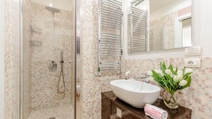 A modern bathroom with a glass-enclosed shower, a white sink, and a mirror above it.