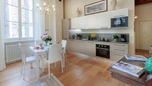 A modern kitchen with white cabinets, a microwave, and a dining area with a table and chairs. - Casa Ugolino in Lucca (Lucca)